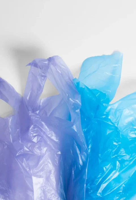 Imagem de sacolas plásticas verdes e azuis, destacando a fabricação sustentável de sacolas para branding ecológico e posicionamento de marca.