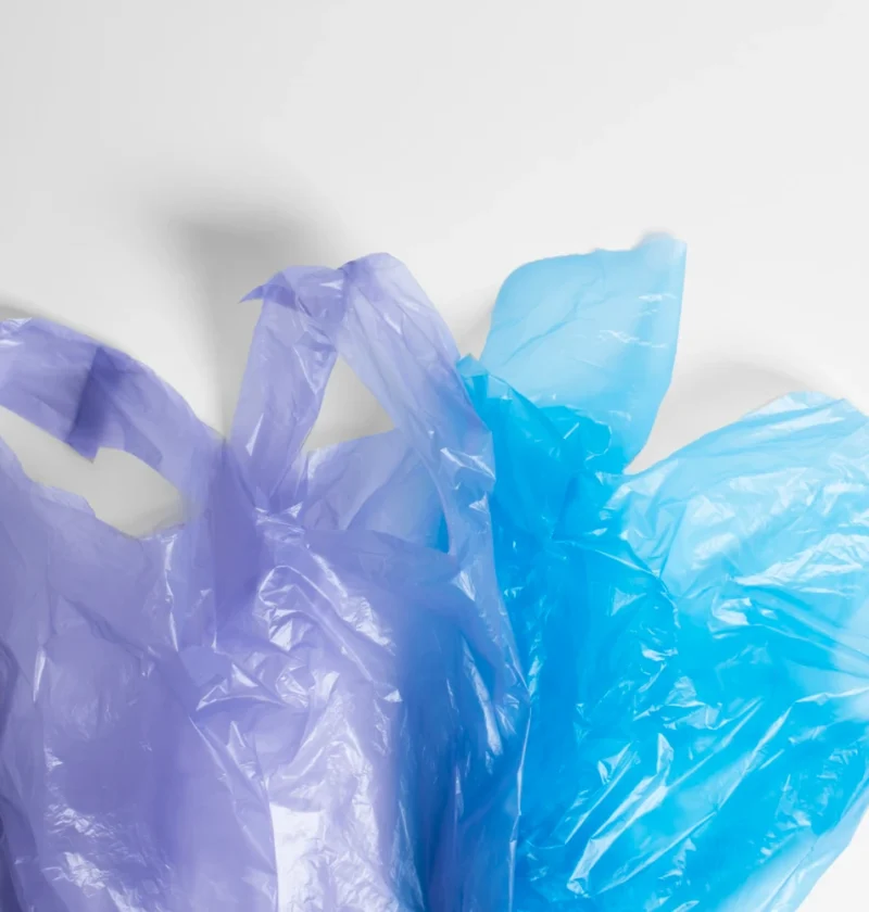 Imagem de sacolas plásticas verdes e azuis, destacando a fabricação sustentável de sacolas para branding ecológico e posicionamento de marca.