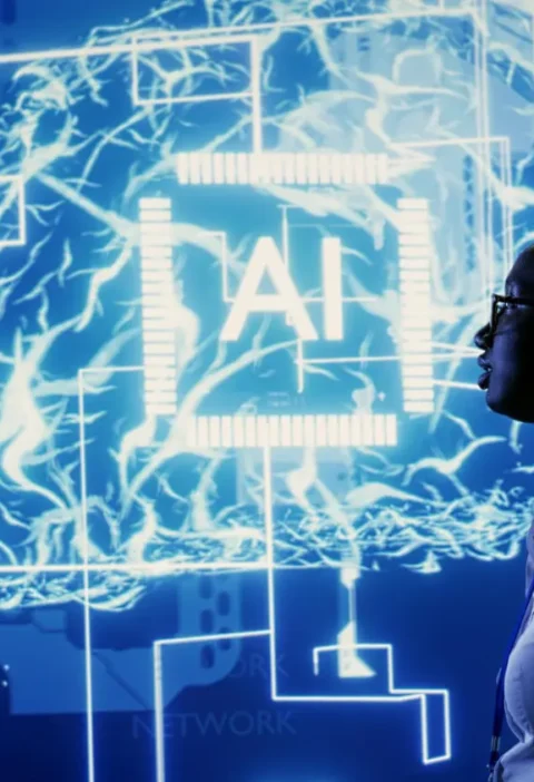 Cena de dois profissionais em silhueta conversando diante de um painel holográfico com símbolos de IA e circuitos digitais, simbolizando Inteligência Artificial: Como a tecnologia está mudando diferentes profissões.