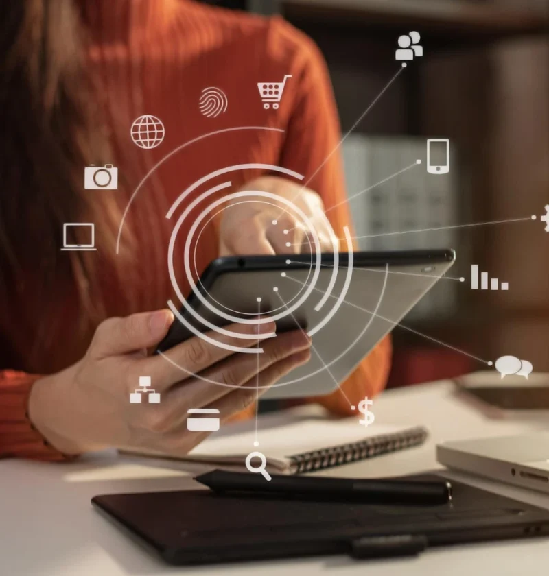 Pessoa usando tablet com ícones digitais e conexão de rede ao fundo, representando Transformação Digital: Como empresas estão se adaptando ao novo consumidor em um ambiente de trabalho moderno.